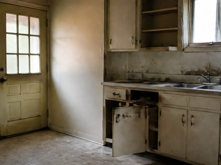 A dated, cluttered kitchen, illustrating the kind of condition JT buys in